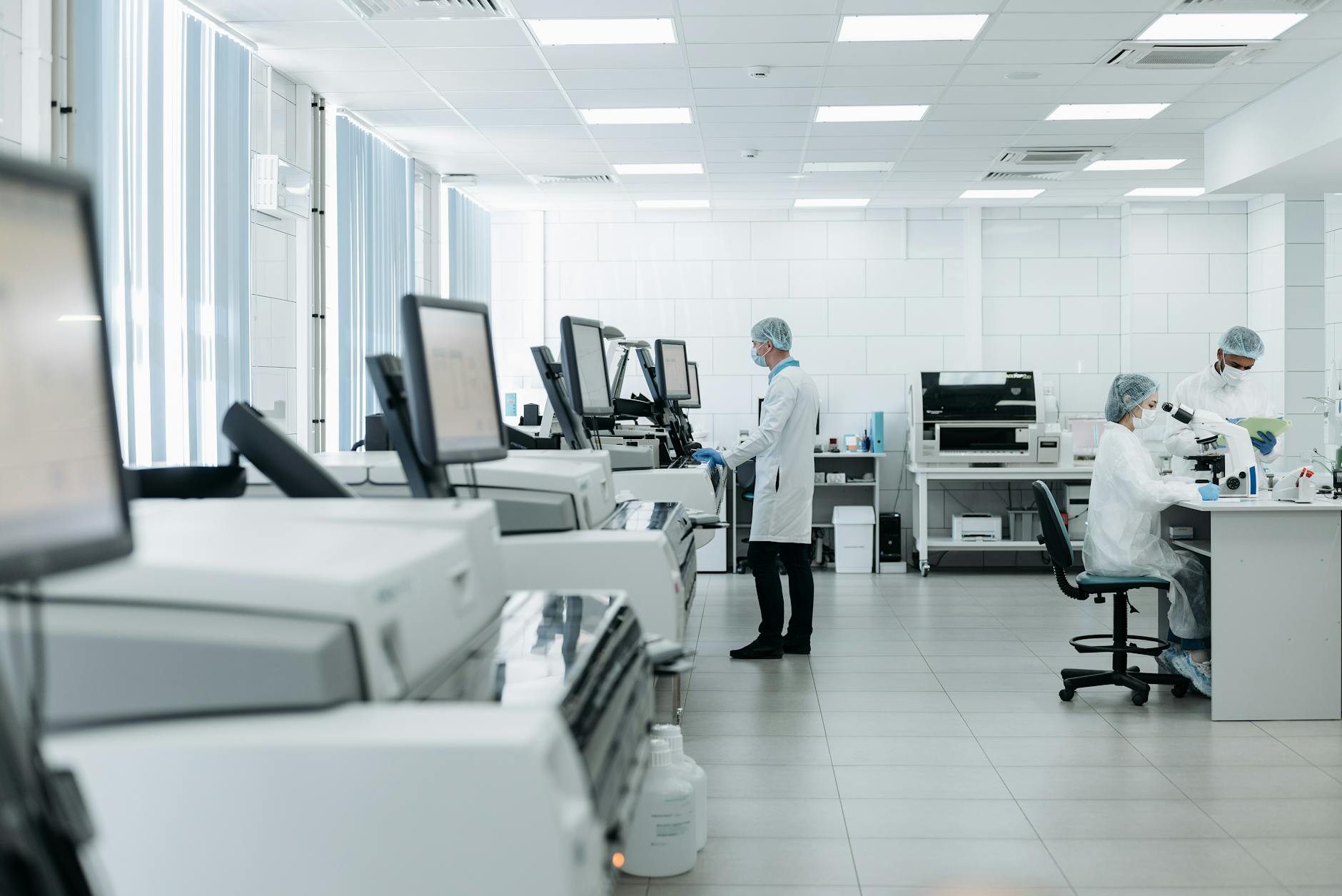 Researchers in a lab looking at empty equipment benches, a notice pinned on the wall