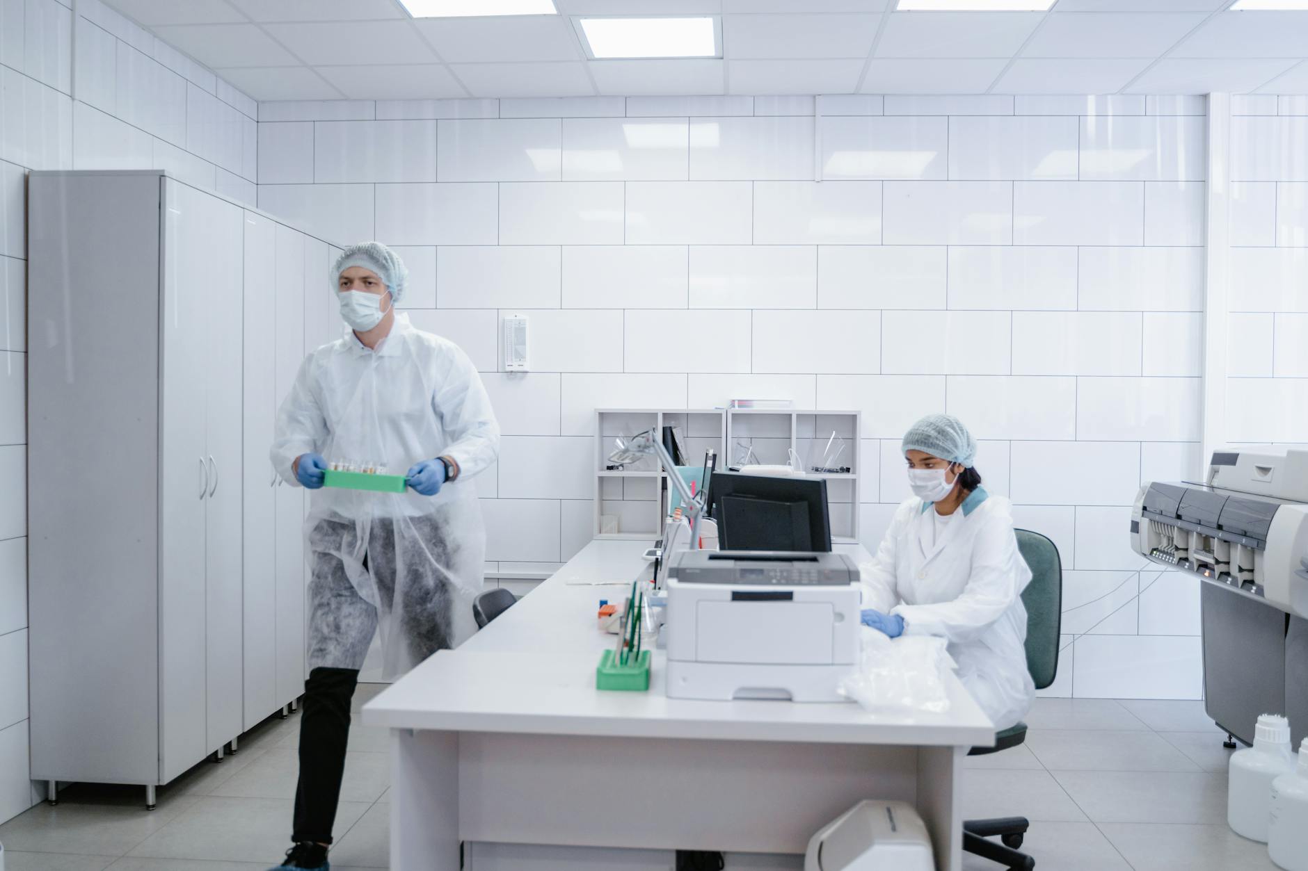 A graduate student packing up lab notebooks and equipment into a box, the lab lights dimming