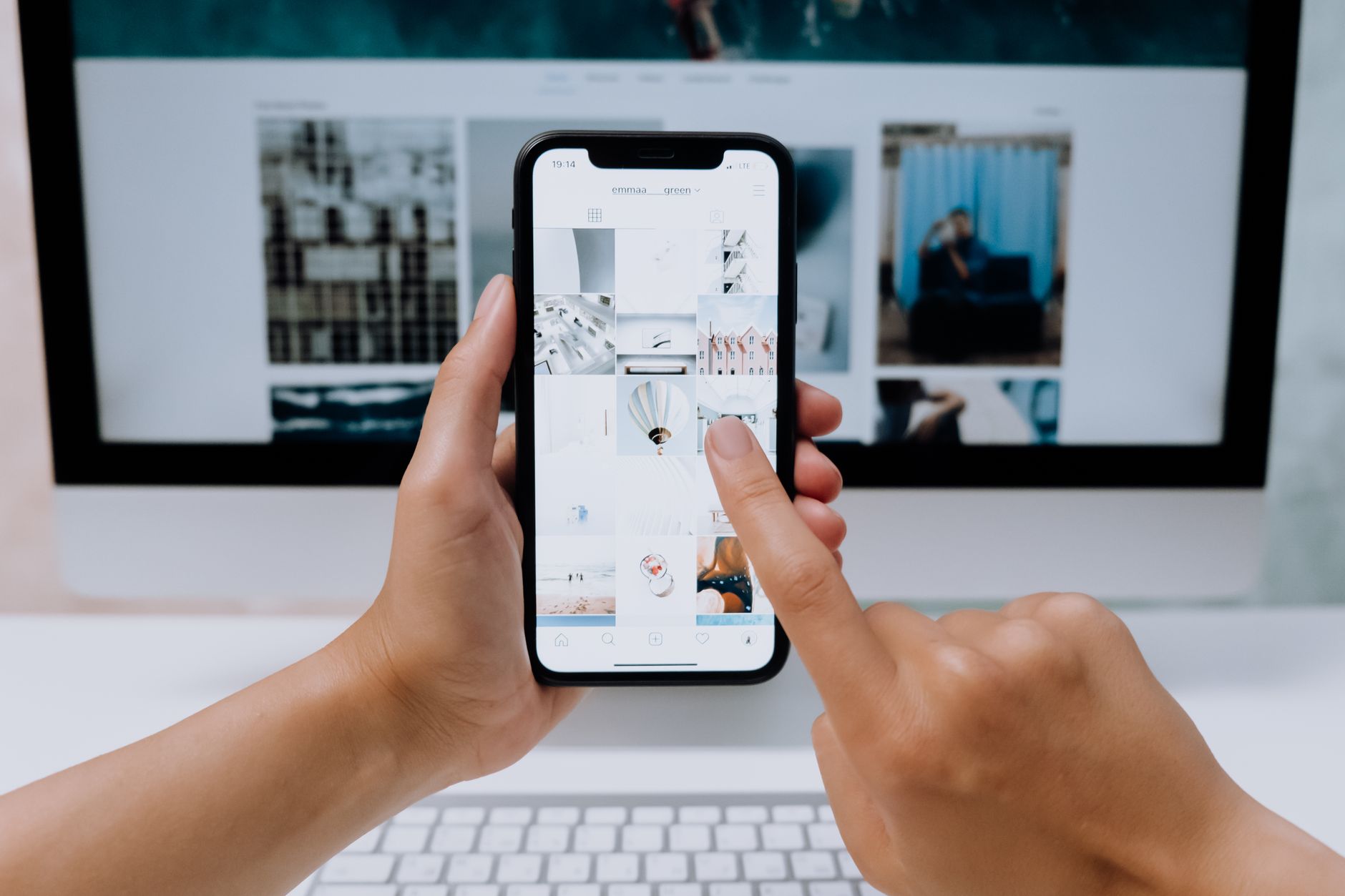 Seseorang menggulir feed media sosial di layar komputer di meja kantor