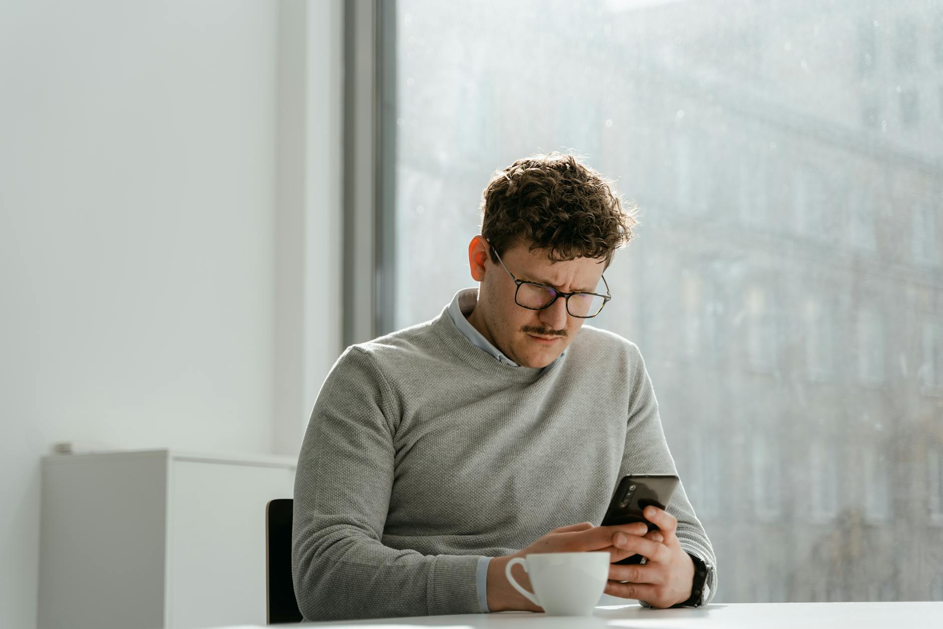 A European procurement manager reading a generic product email on their phone, subtle look of disinterest, natural daylight office