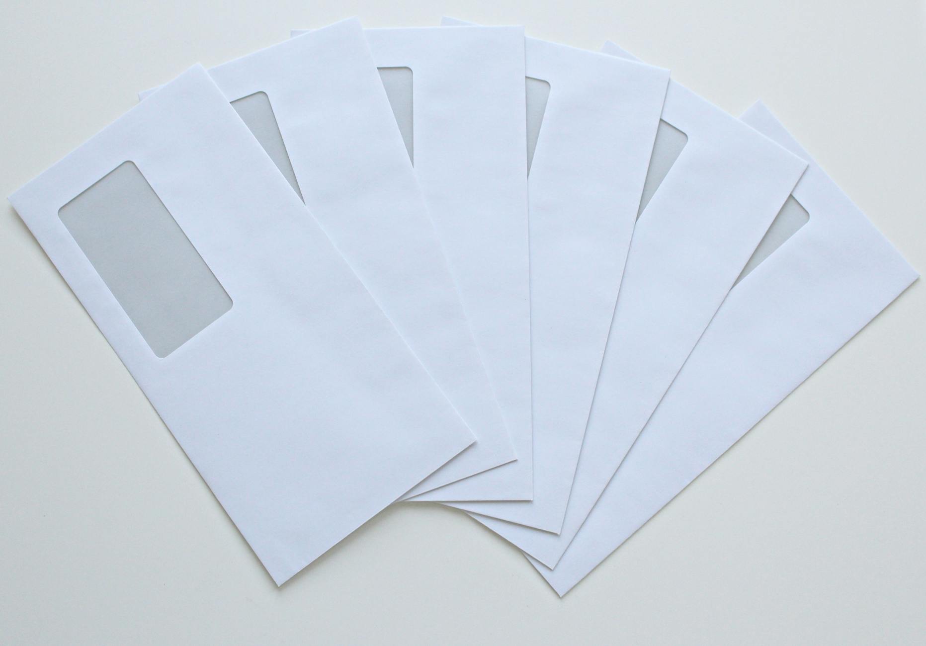Dozens of identical envelopes moving along a conveyor belt