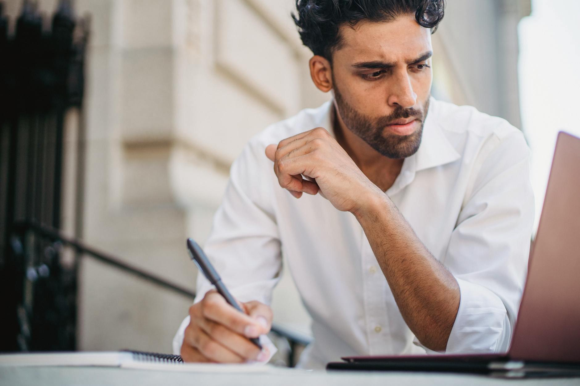 An export professional reviewing a draft email on a laptop screen, annotating with a pen