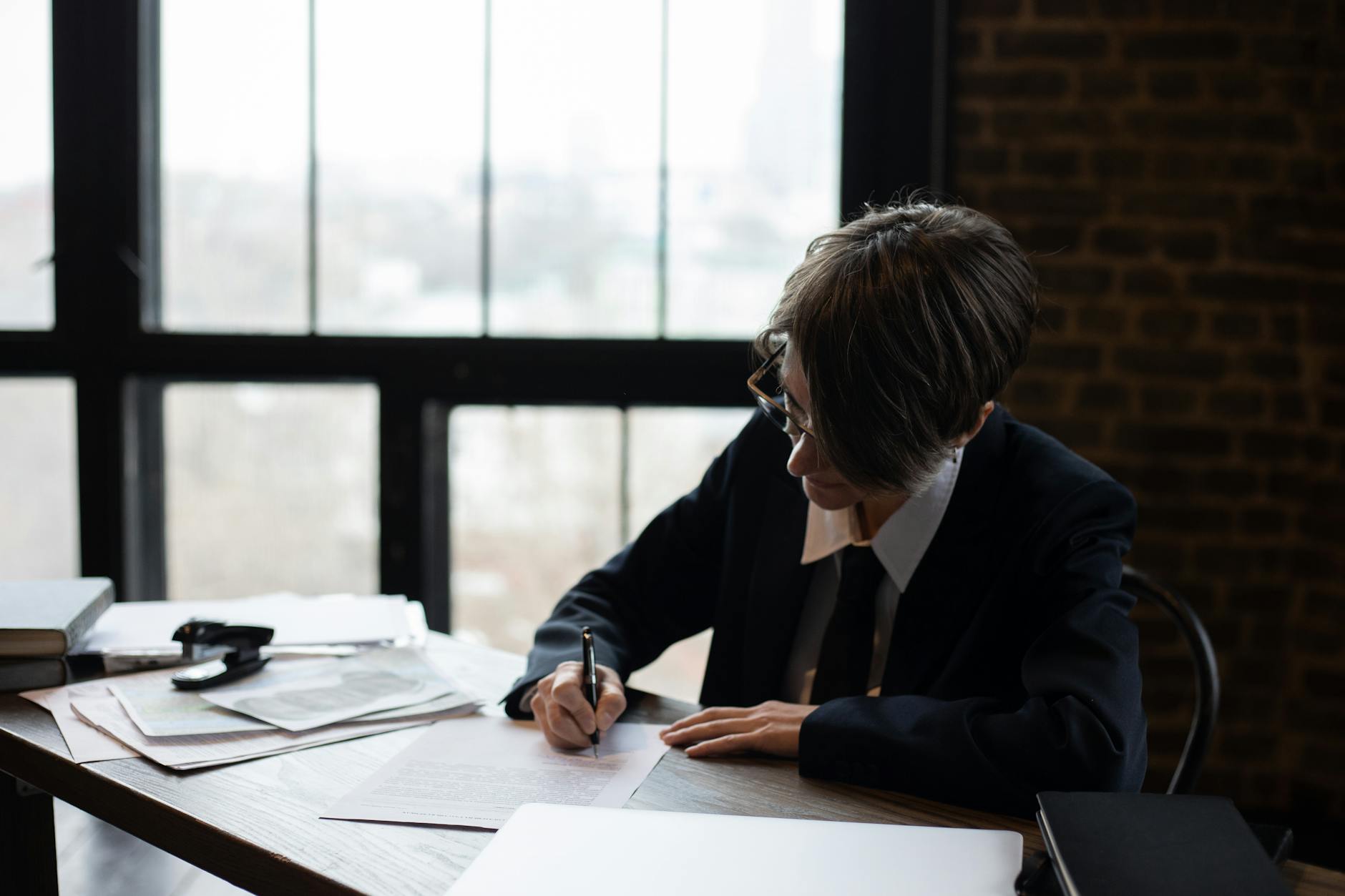 An export professional focused at a desk by a window, writing a checklist in a notebook