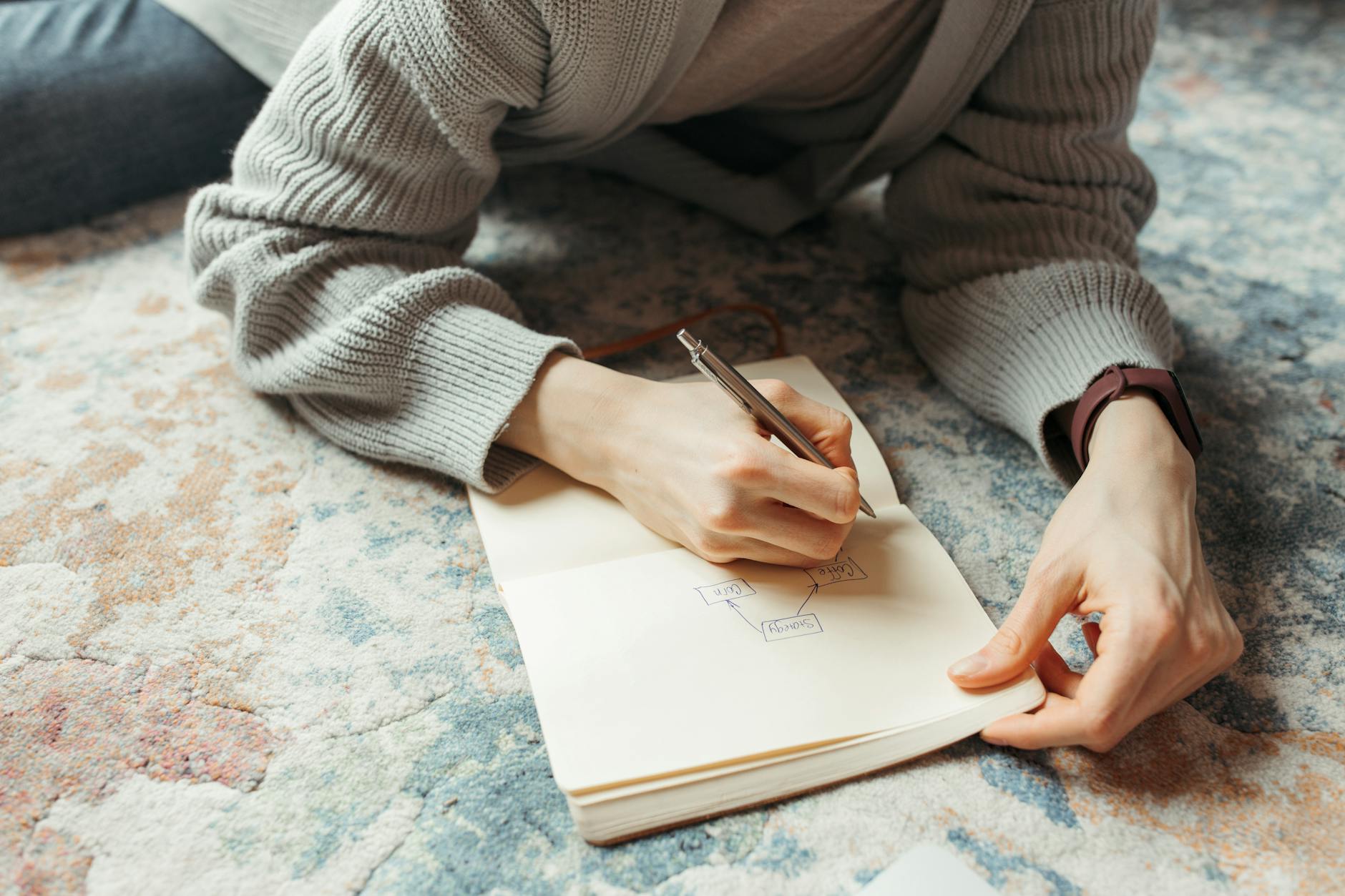 A developer sketching a flowchart by hand in a notebook, thinking alone at a café