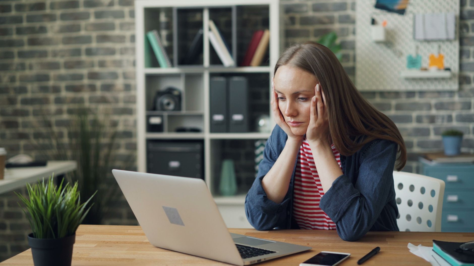 A small business owner at a desk, frowning slightly while reading an email notification about a software price change