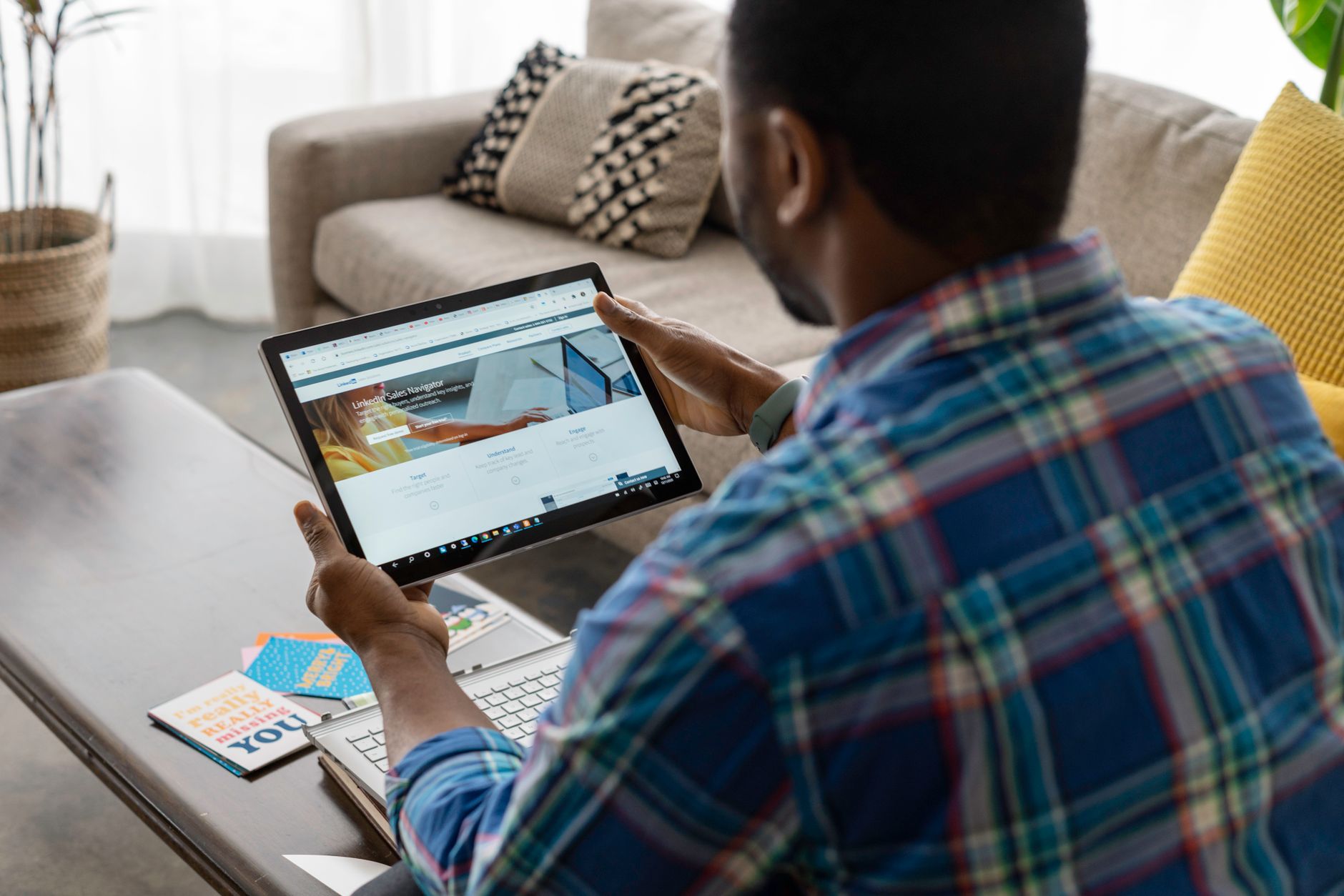 A clean tablet screen displaying a professional LinkedIn feed with a blurred corporate logo in the background.