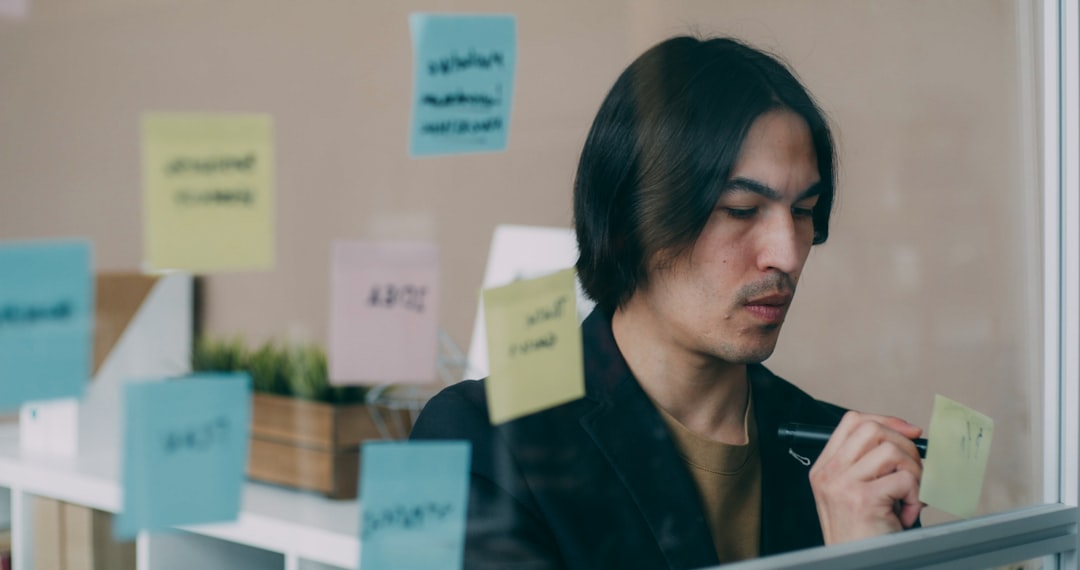 Seorang profesional mencatat di buku sambil memandang ke luar jendela