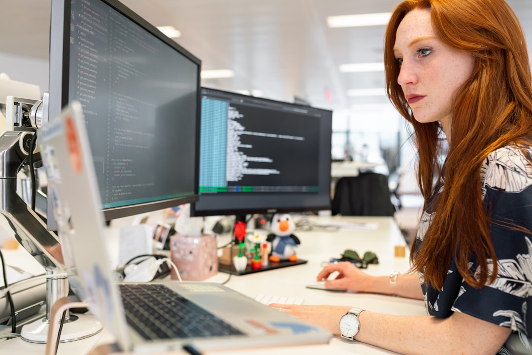 A software engineer working late at night, analyzing genomic data pipelines with 3D double-helix visualizations on a dual-monitor setup, clean modern office